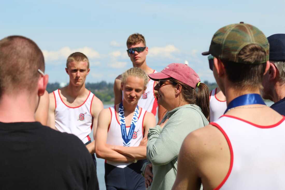 Coach Liza Dickson stands talking to her junior boys rowers before a regatta. 