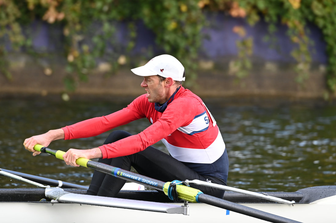 A male rower strains as he rows during a regatta. 